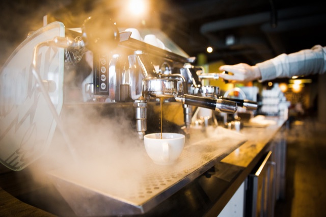 Buharın içinde espresso makinesinden fincana akan kahve